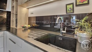 A modern kitchen with a black countertop, stainless steel sink, and a potted plant.