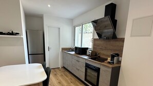 Una cocina moderna con encimera blanca, electrodomésticos de acero inoxidable y suelo de madera.
