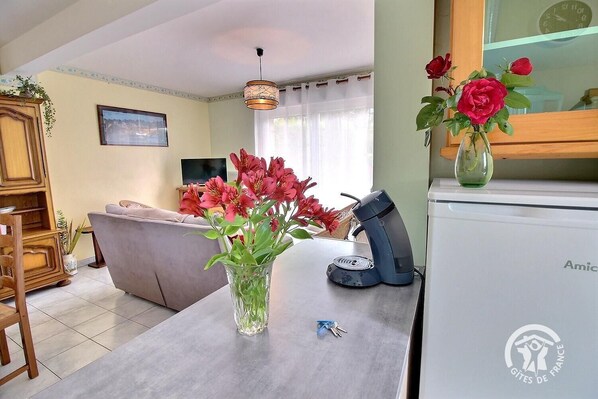 Ein Wohnzimmer mit einer Couch, einem Couchtisch mit Blumenvase, einem Fernseher und einer Wanduhr.