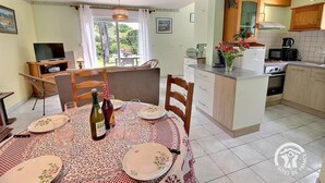 Een gezellige keuken met een eethoek, met een tafel gedekt voor twee personen, een televisie en uitzicht op de omgeving.