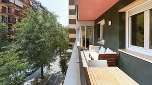 A balcony with outdoor seating, a view of a tree-lined street, and a building with striped architecture in the background. - Family Apartment Camp Nou by Maison Piñata (Barcelona)