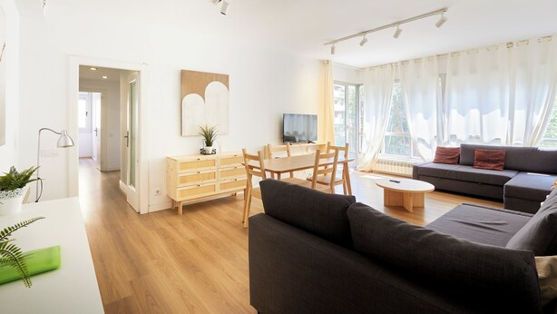 A modern living room with a sofa, dining table, and TV. - Family Apartment Camp Nou by Maison Piñata (Barcelona)