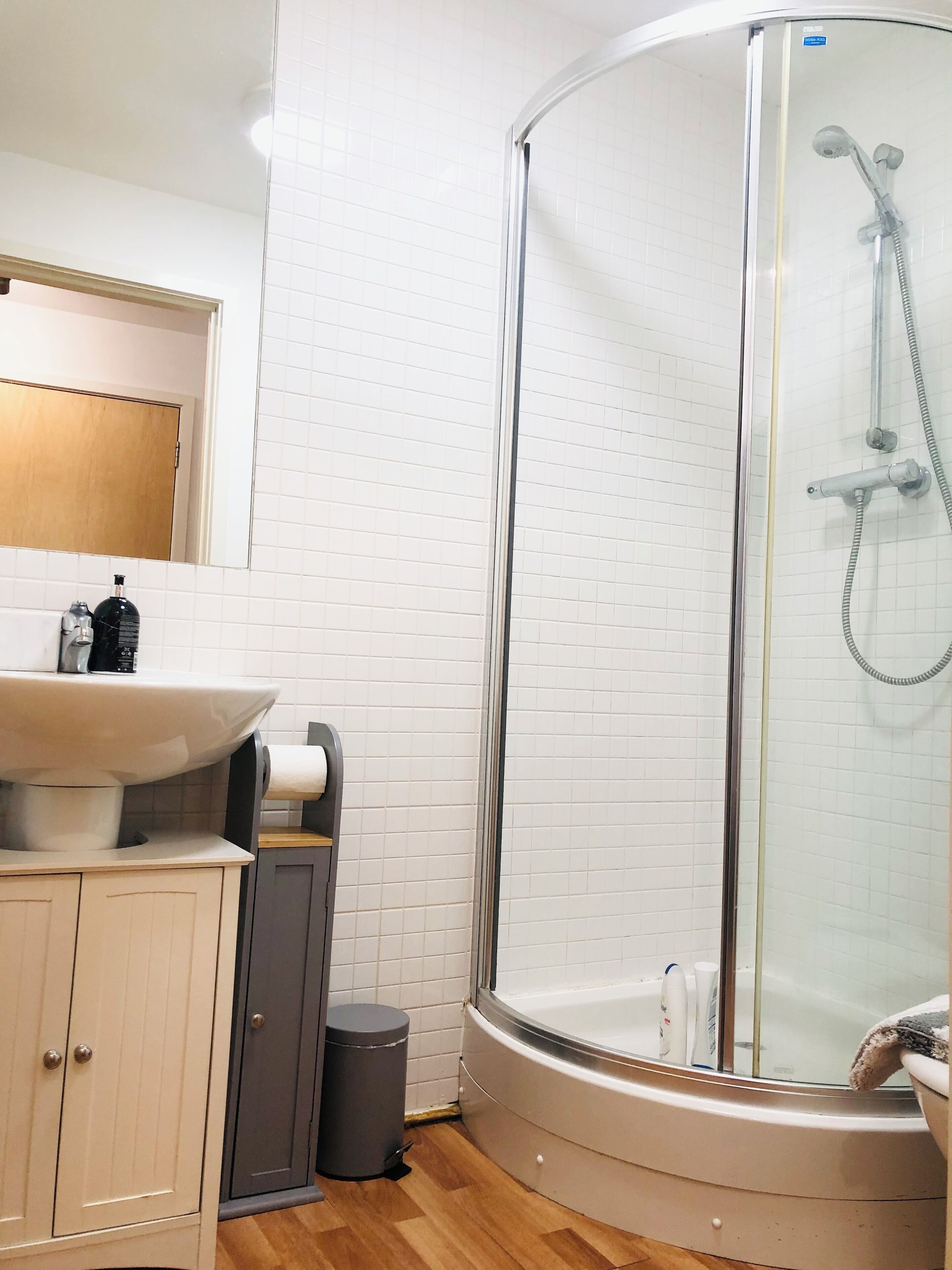 Een moderne badkamer met een douchecabine van glas, een wastafel met spiegel erboven en een toilet.
