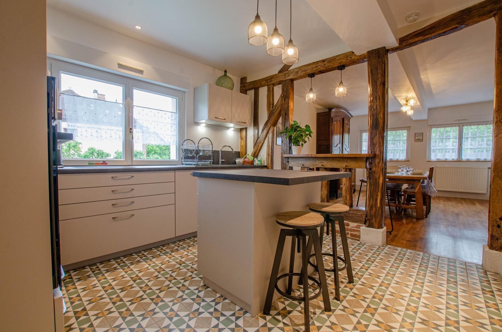 Uma cozinha com ilha central, banquetas e uma área de refeições com mesa e cadeiras de madeira.