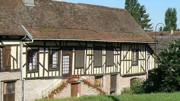 Uma casa tradicional em estilo de enxaimel, com telhado inclinado, porta de madeira e um pequeno alpendre florido.