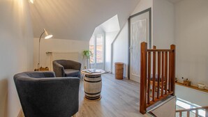 Ein modernes Loft mit hohen Decken, einer Holztreppe und einer gemütlichen Sitzecke mit einem runden Tisch und zwei Sesseln.