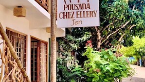 Naamplaatje voor Pousada Chez Ellery in Jeri, met een traditioneel ontwerp, houten leuning en weelderige begroeiing.