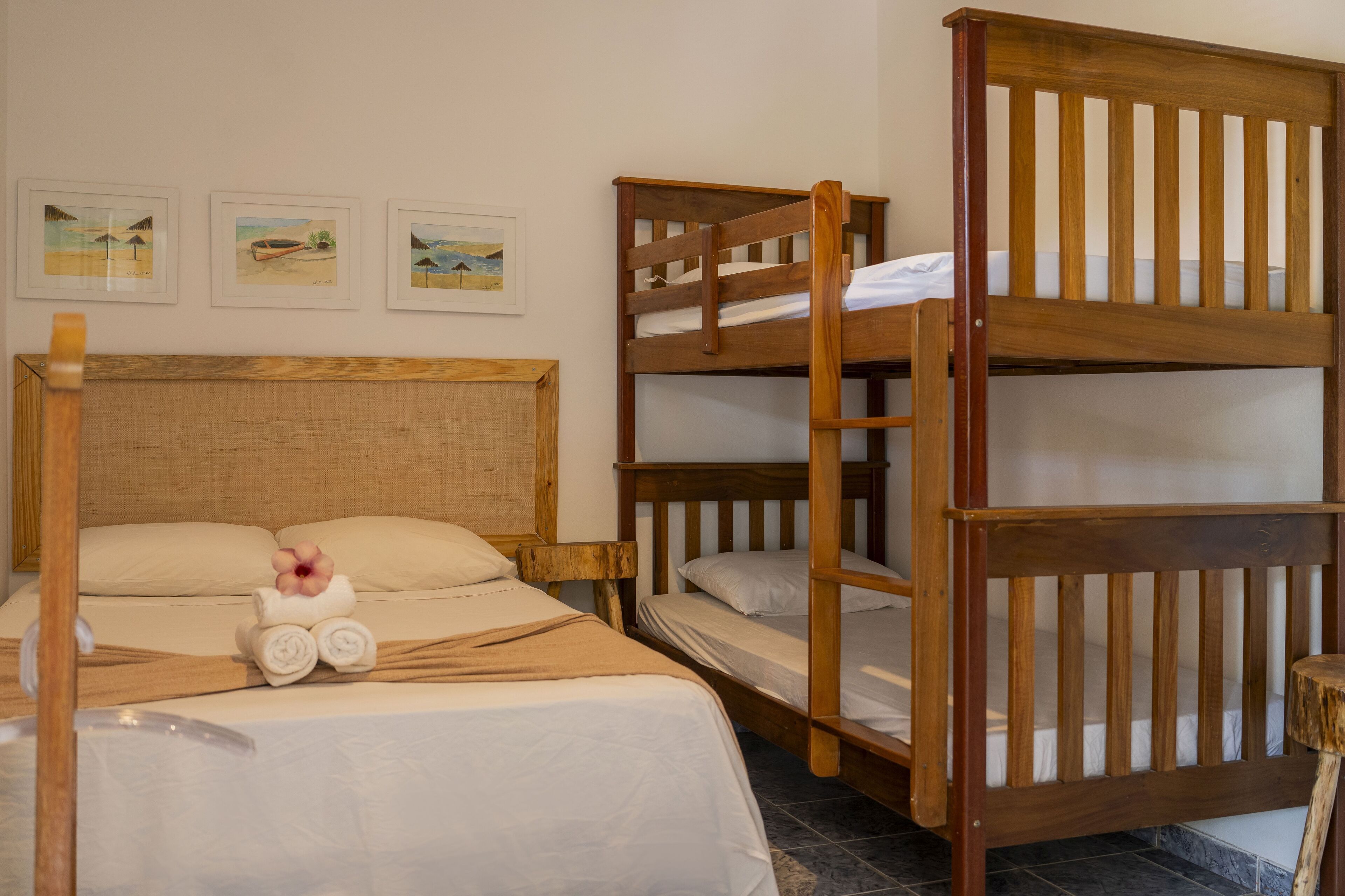 A room with a single bed, two bunk beds, and three framed pictures on the wall.