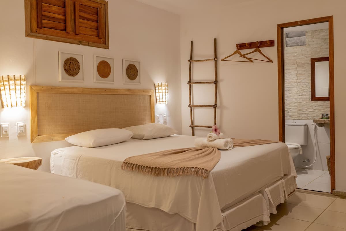 Ein Hotelzimmer mit einem großen Bett, einem Holz-Kopfteil, einer Leiter und einem durch eine offene Tür einsehbaren Badezimmer.