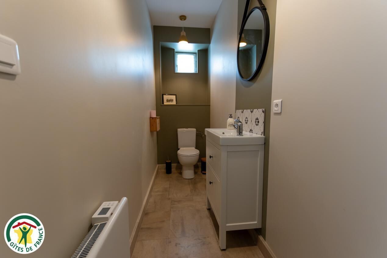 Un baño estrecho con inodoro, lavamanos y una ventana pequeña.