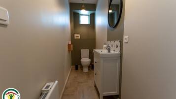 Un baño estrecho con inodoro, lavamanos y una ventana pequeña.