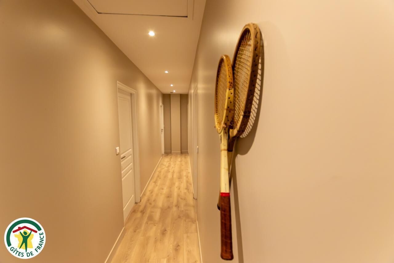 Ein Flur mit Holzboden und einem an der Wand angelehnten Tennisracket.