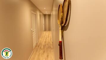 Ein Flur mit Holzboden und einem an der Wand angelehnten Tennisracket.