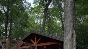 Une cabane rustique avec un porche, un petit sapin de Noël et une lanterne.