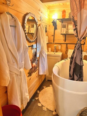 Ein Holzinnenraum mit einer großen Badewanne, Holzschränken und einem Spiegel.