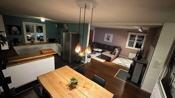 A modern kitchen with a wooden dining table, a refrigerator, and pendant lights.