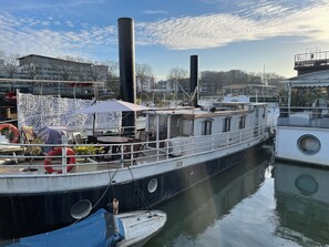 A docked boat with a covered seating area and a lifebuoy. - Paris au fil de l'eau - Boat Rentals (Paris)