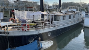 A boat docked at a marina with a covered seating area and a lifebuoy.