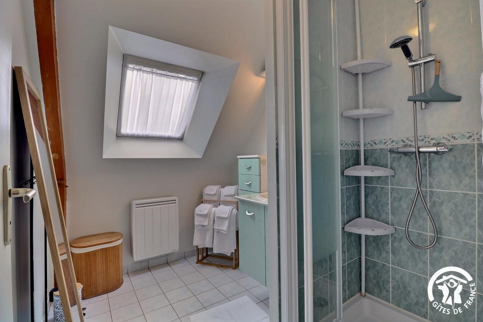 Een moderne badkamer met dakraam, douche en een klein kastje.