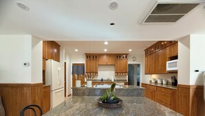 A modern kitchen with granite countertops, wooden cabinets, and a central island with plants.