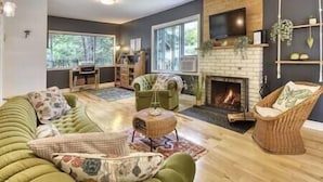 Ein modernes Wohnzimmer mit Kamin, grünen Sofas und einem Fernseher.