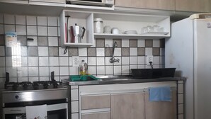 A kitchen with a stove, microwave, sink, and a refrigerator. - Edifício Flat Euro (Natal)