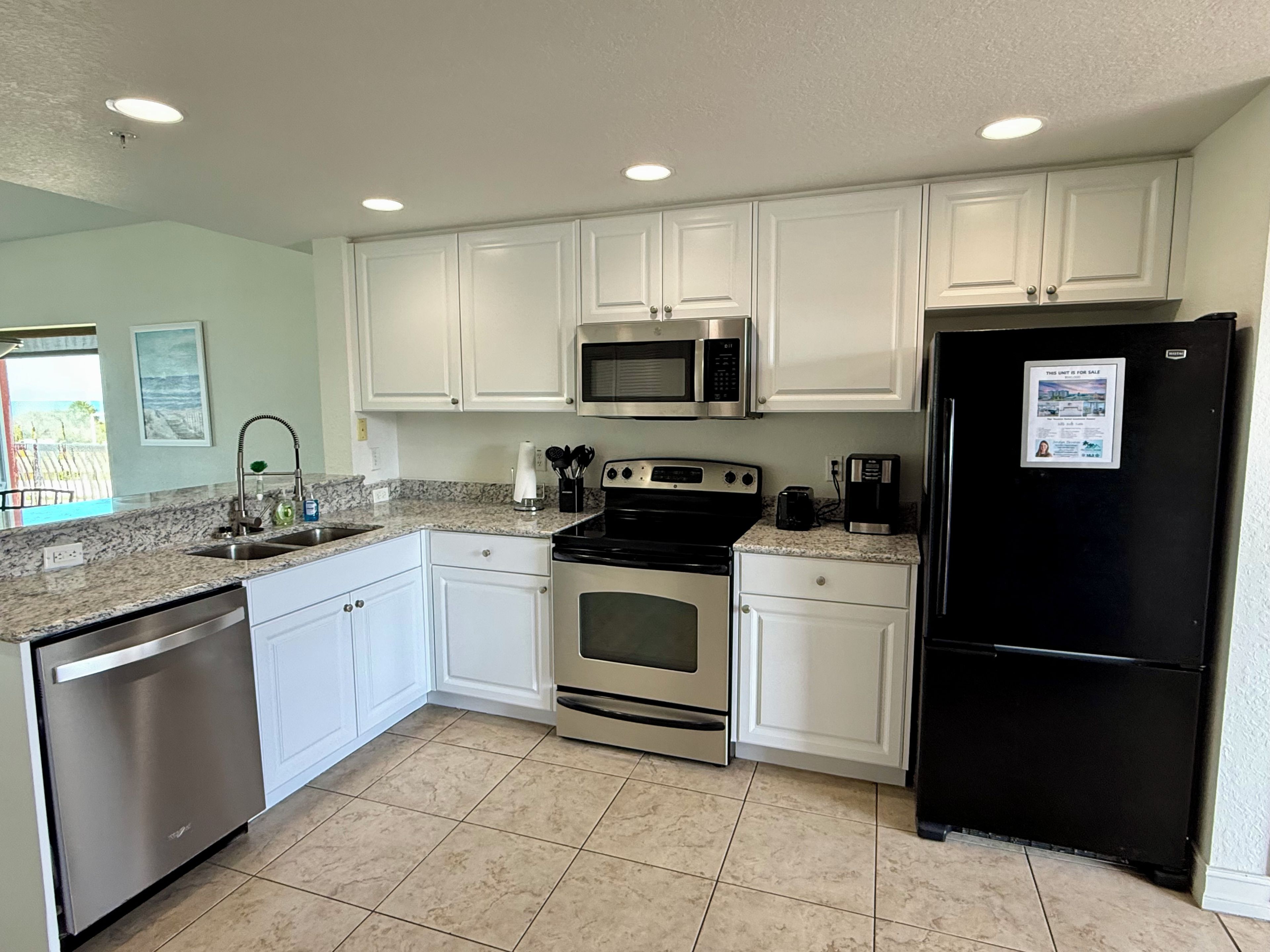 A kitchen with white cabinets, stainless steel appliances, and a black refrigerator.