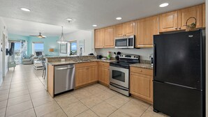 Una cocina moderna con armarios de madera, electrodomésticos de acero inoxidable y suelo de baldosas.