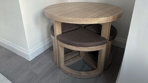 Une table ronde en bois avec des sièges rembourrés.