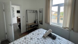 Une chambre à coucher avec un lit, une armoire, une fenêtre avec des rideaux et un radiateur.