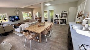 Un salon spacieux avec une table à manger en bois, des sièges confortables, un téléviseur et une bibliothèque.