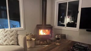 Un salon chaleureux avec un poêle à bois, un canapé, une table basse et une bibliothèque.