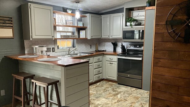 A compact kitchen with white cabinets, a central island, bar stools, and a built-in oven.