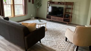 A living room with a sofa, armchair, coffee table, and TV stand.