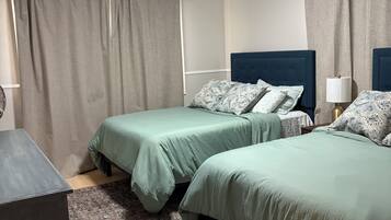 Hotellihuone, jossa on kaksi sänkyä, työpöytä, lamppu ja kuviollinen matto.