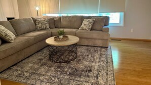 A modern living room with a sectional sofa, a round coffee table, and a patterned rug. - Clarkston House with pool! Relax and enjoy with family and friends (Clarkston)