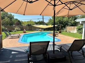 A backyard with a swimming pool, lounge chairs, and a covered patio area. - Clarkston House with pool! Relax and enjoy with family and friends (Clarkston)