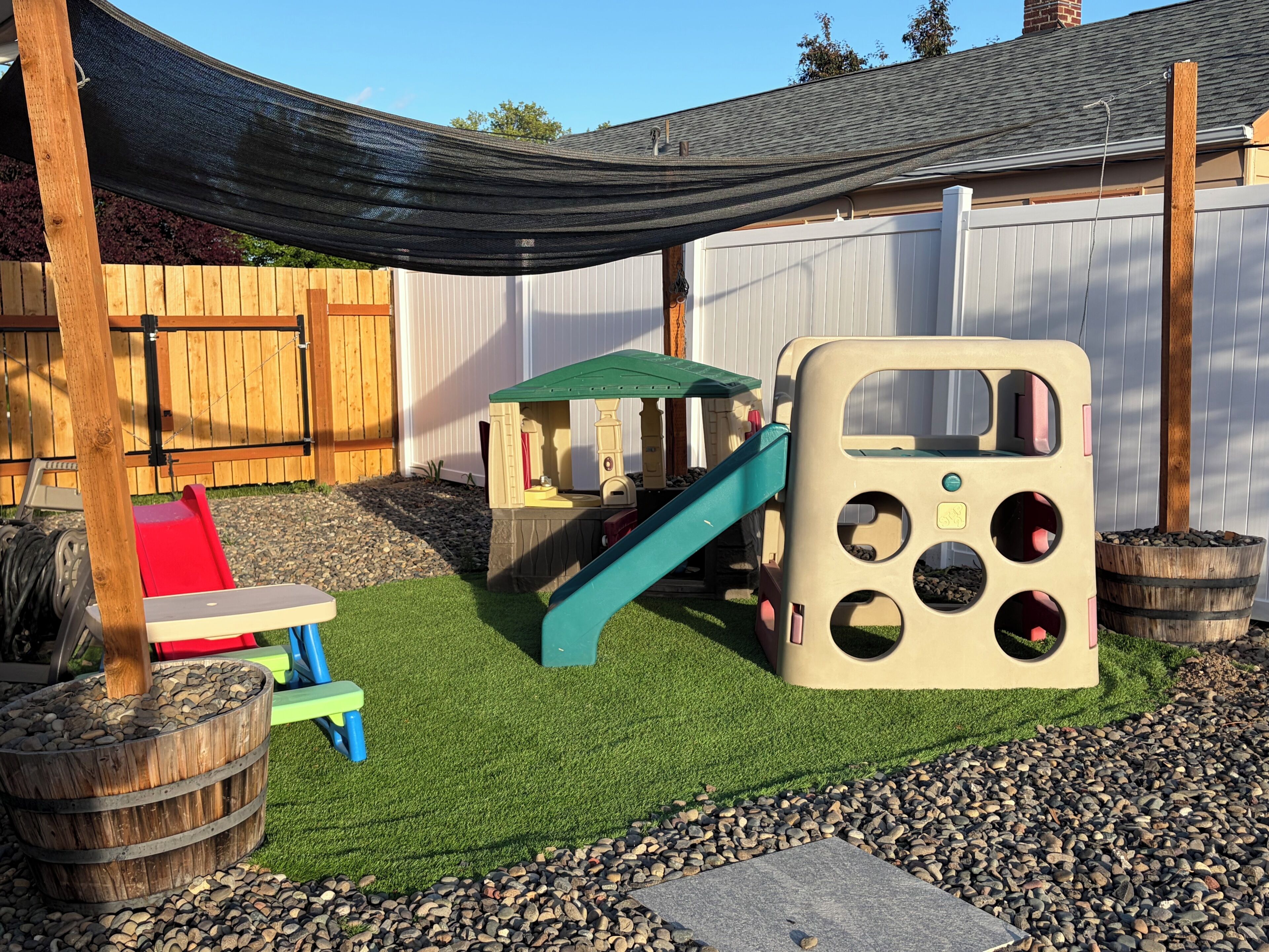 A children's play area with a slide, playhouse, and a shaded seating area.