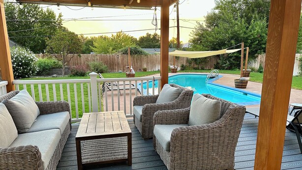 A covered outdoor deck with wicker furniture, a pool, and a wooden deck. - Clarkston House with pool! Relax and enjoy with family and friends (Clarkston)
