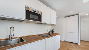 Een moderne keuken met een roestvrijstalen spoelbak, een houten aanrechtblad, witte kastjes, een ingebouwde oven en een koffiezetapparaat.