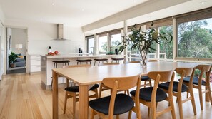 A modern kitchen with a central island, wooden dining table, and chairs. - Pet Friendly - Long View - Heated Pool in Red Hill (Red Hill)