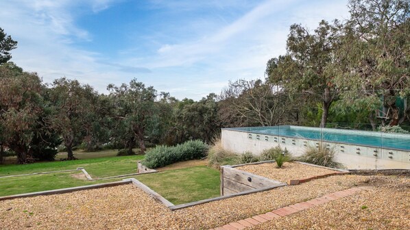 A swimming pool surrounded by a garden with a variety of trees and shrubs.