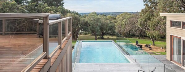 A modern house with a swimming pool, glass-enclosed deck, and a view of the surrounding trees. - Pet Friendly - Long View - Heated Pool in Red Hill (Red Hill)