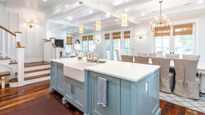 A spacious kitchen with a central island, wooden staircase, and large windows. - WaterColor Cottage with 6 seater golf cart + 6 bikes, 9 pools, beach access! (Santa Rosa Beach)