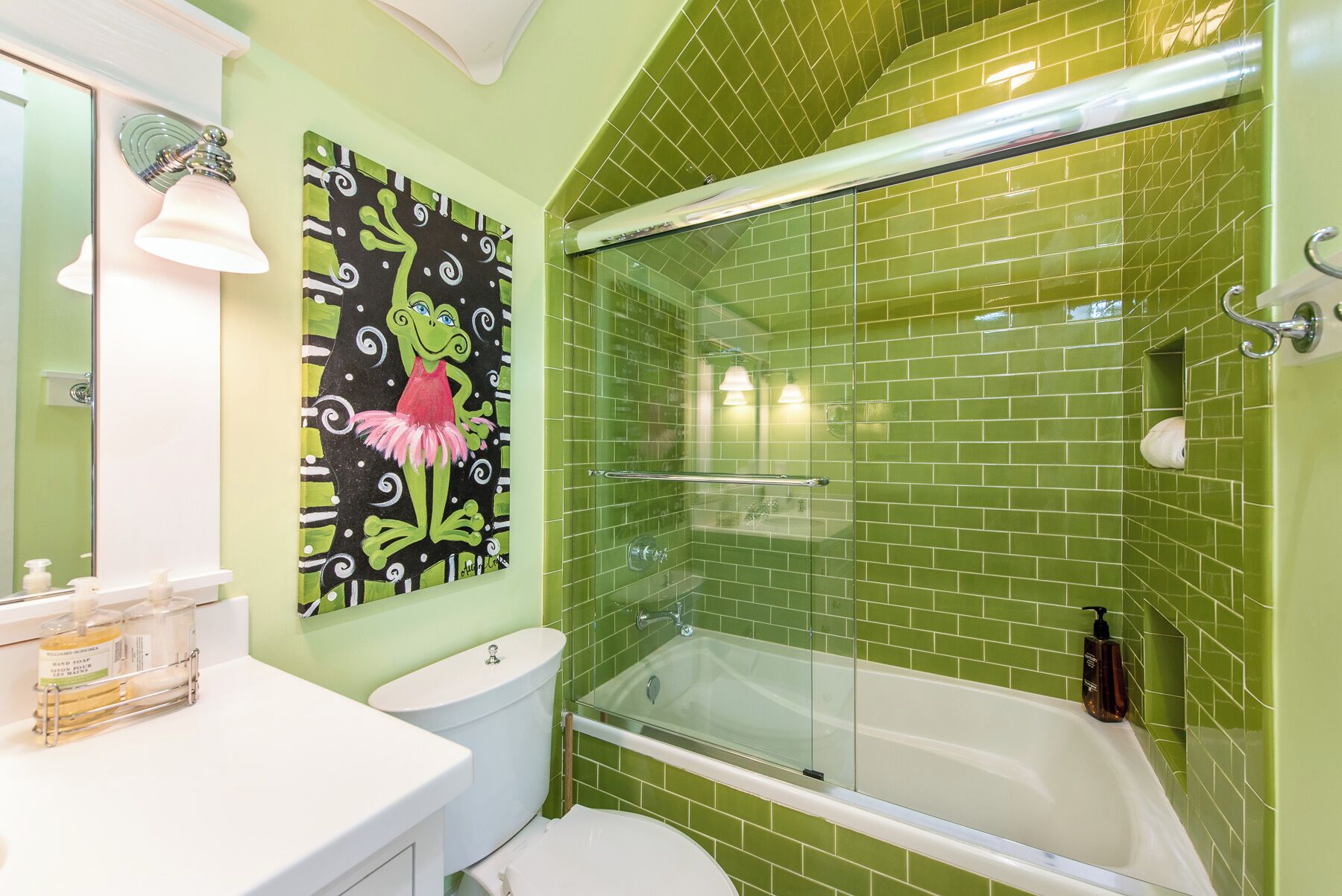 A bathroom with a green tiled shower enclosure, a white bathtub, and a toilet.