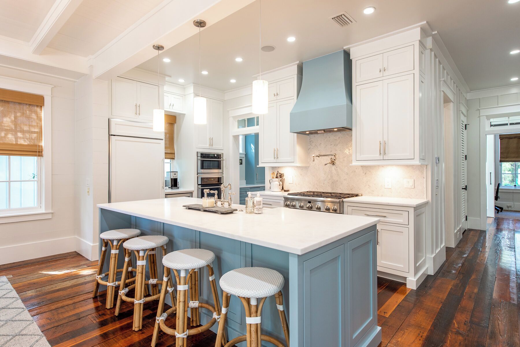 A spacious kitchen with a large island, white cabinetry, and a blue accent wall.