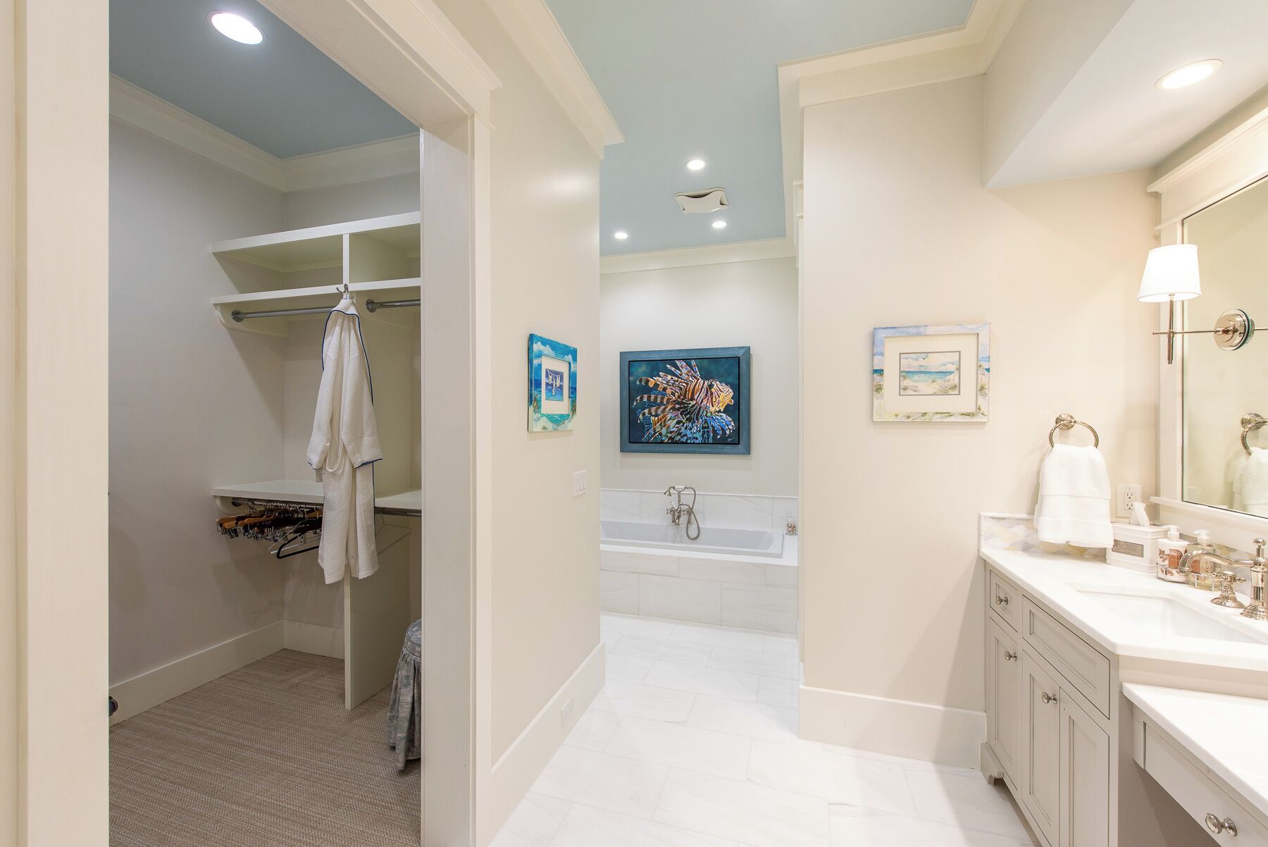 Un bagno con una vasca, un lavandino e uno specchio. Asciugamani appesi a un portasciugamani e un quadro incorniciato al muro.