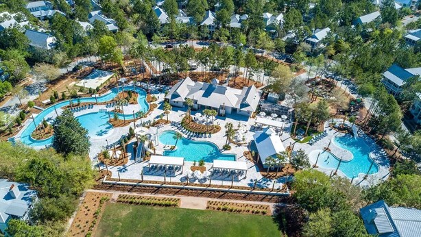 An aerial view of a resort with multiple swimming pools, lounge areas, and a large grassy field. - WaterColor Cottage with 6 seater golf cart + 6 bikes, 9 pools, beach access! (Santa Rosa Beach)