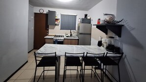 Une cuisine compacte comprenant une table et des chaises, un fourneau, un réfrigérateur et un four à micro-ondes.