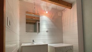 Ein kleines Badezimmer mit Waschbecken, Spiegel und Waschmaschine.